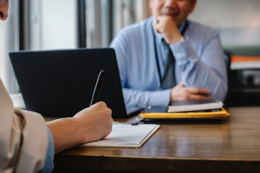 A lender explaining something as a small business owner is writing something down.