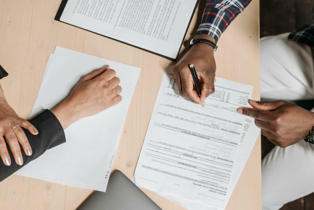 A businessperson helps someone fill out a form.